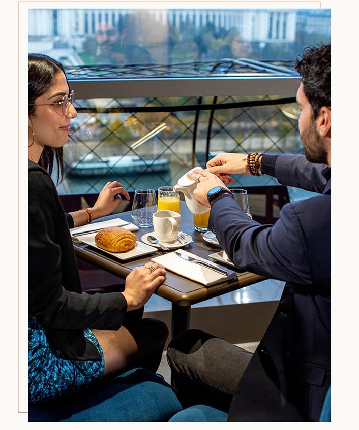 A couple having a Parisian breakfast on the Eiffel tower at Madame Brasserie